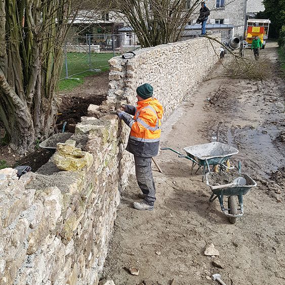 Construction d'un mur en pierre sèche de récupération , montage au mortier maigre alignement des pierres